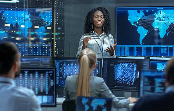 People working in data communications room with monitors and large screens