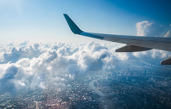 Wing of airplane in flight over city scape below