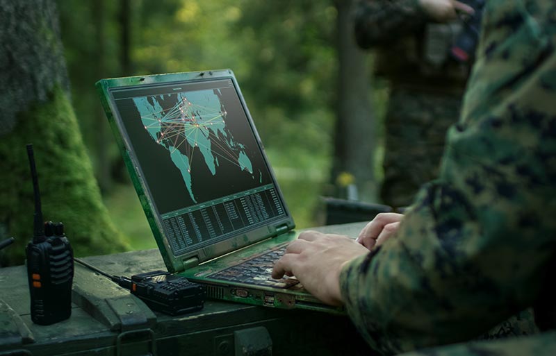Military person using laptop and radios for military communications