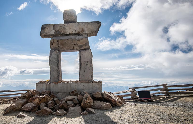 Large inukshuk at the top of cliff looking out to the open sky