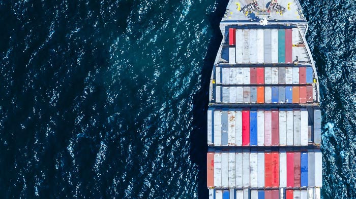 High angle shot looking down at cargo ship as it travels across frame