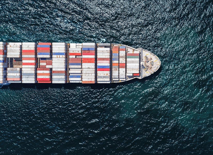 High angle shot looking down at cargo ship as it travels across frame