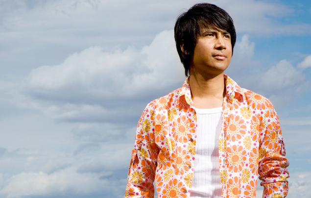 Young First Nations male standing in front of a blue sky