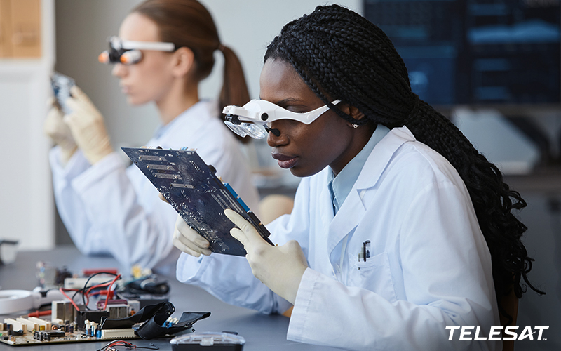 Two young female students in lab with special glasses looking at computer boards