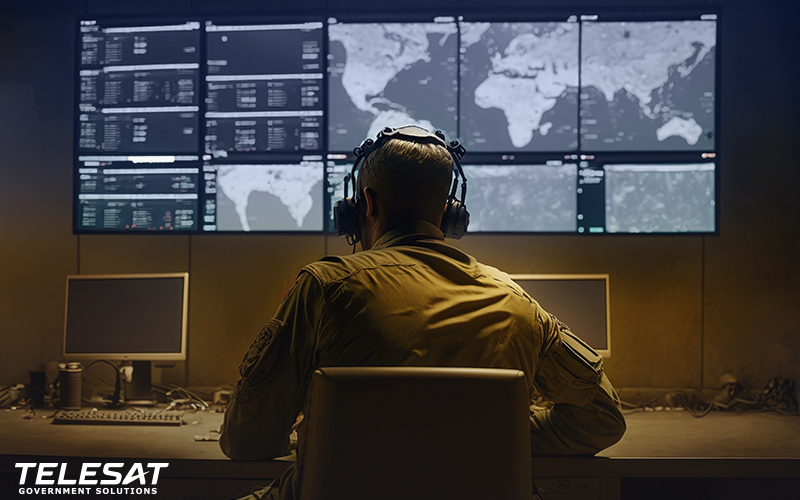 Military person sitting in front of bank of monitors in a control room