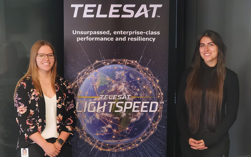 Shaylene Abrey-Webster and Landys Lepine standing on either side of Telesat Lightspeed banner