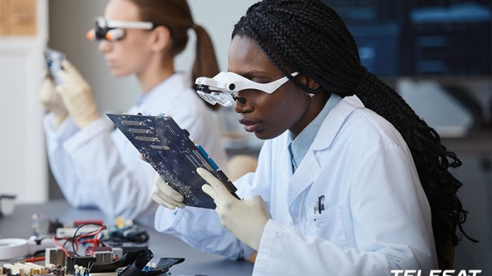 Two young female students in lab with special glasses looking at computer boards