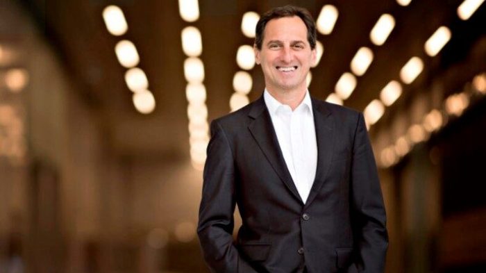 Dan Goldberg standing in corporate headquarters hallway with decorative lighting overhead.