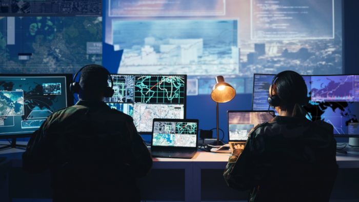 Military operators review satellite imagery and network data, representing digital engineering and MBSE in defense operations.