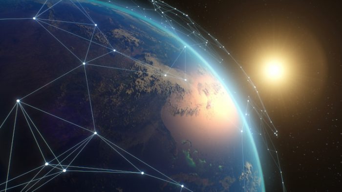 Earth viewed from space with a digital network overlay connecting points across the globe, symbolizing satellite-enabled global connectivity, with sunlight illuminating the planet’s edge